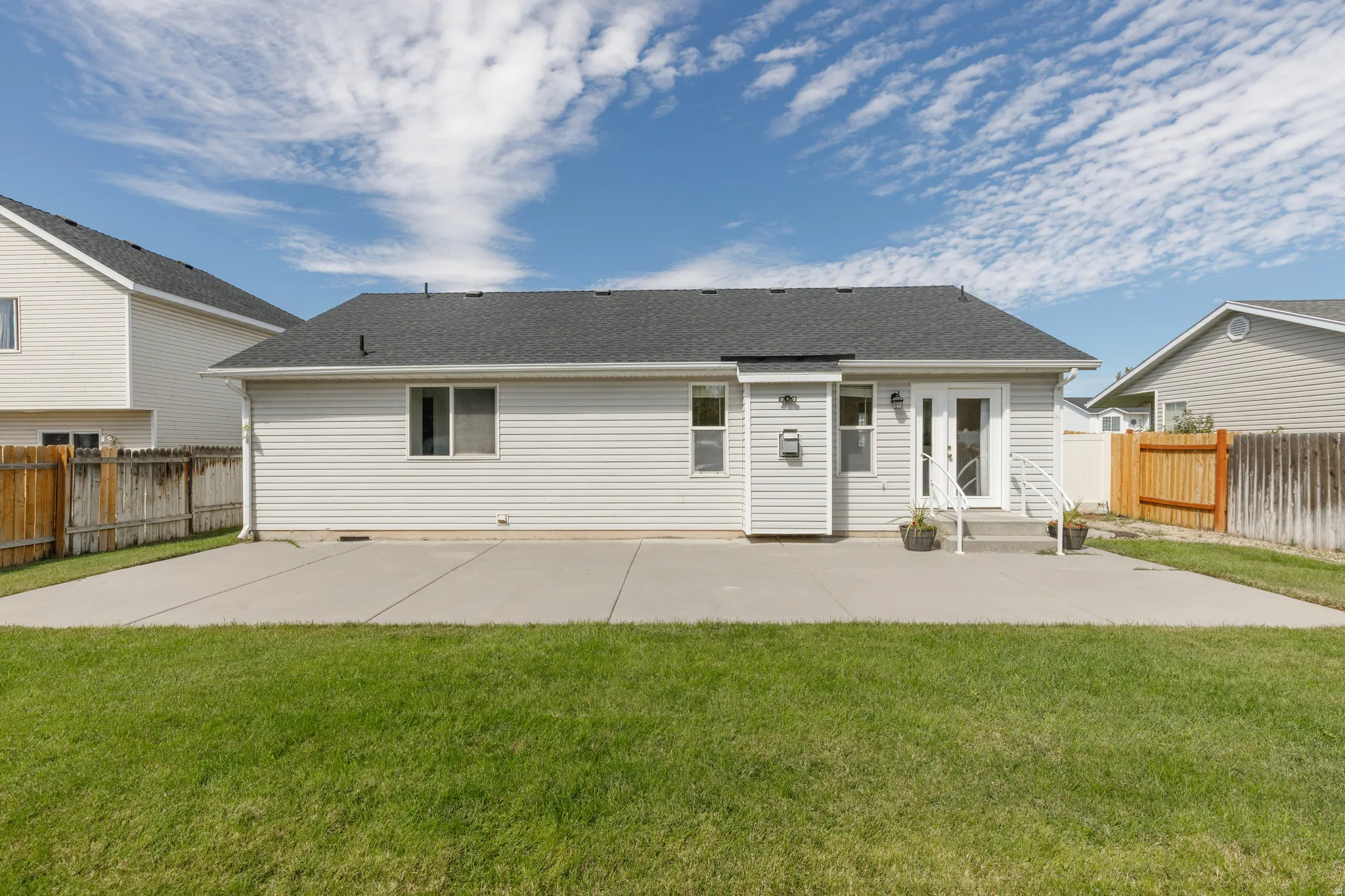 Expansive rear concrete patio with direct access to the interior via double French doors