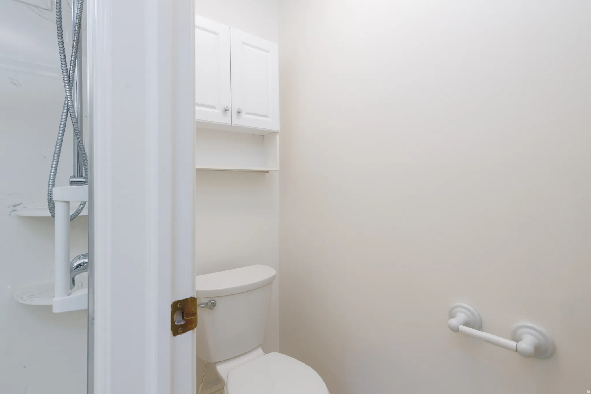 White built-in cabinetry with open shelving, toilet, and shower with chrome fixtures