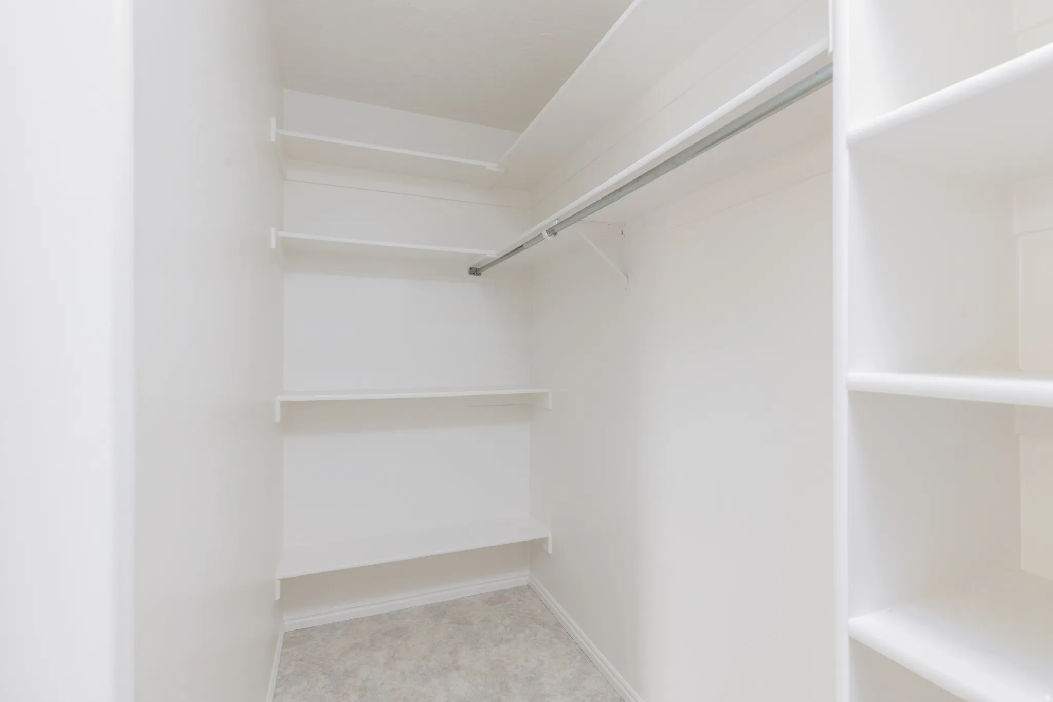 Built-in shelving, hanging rod, and light-colored wall-to-wall carpeting