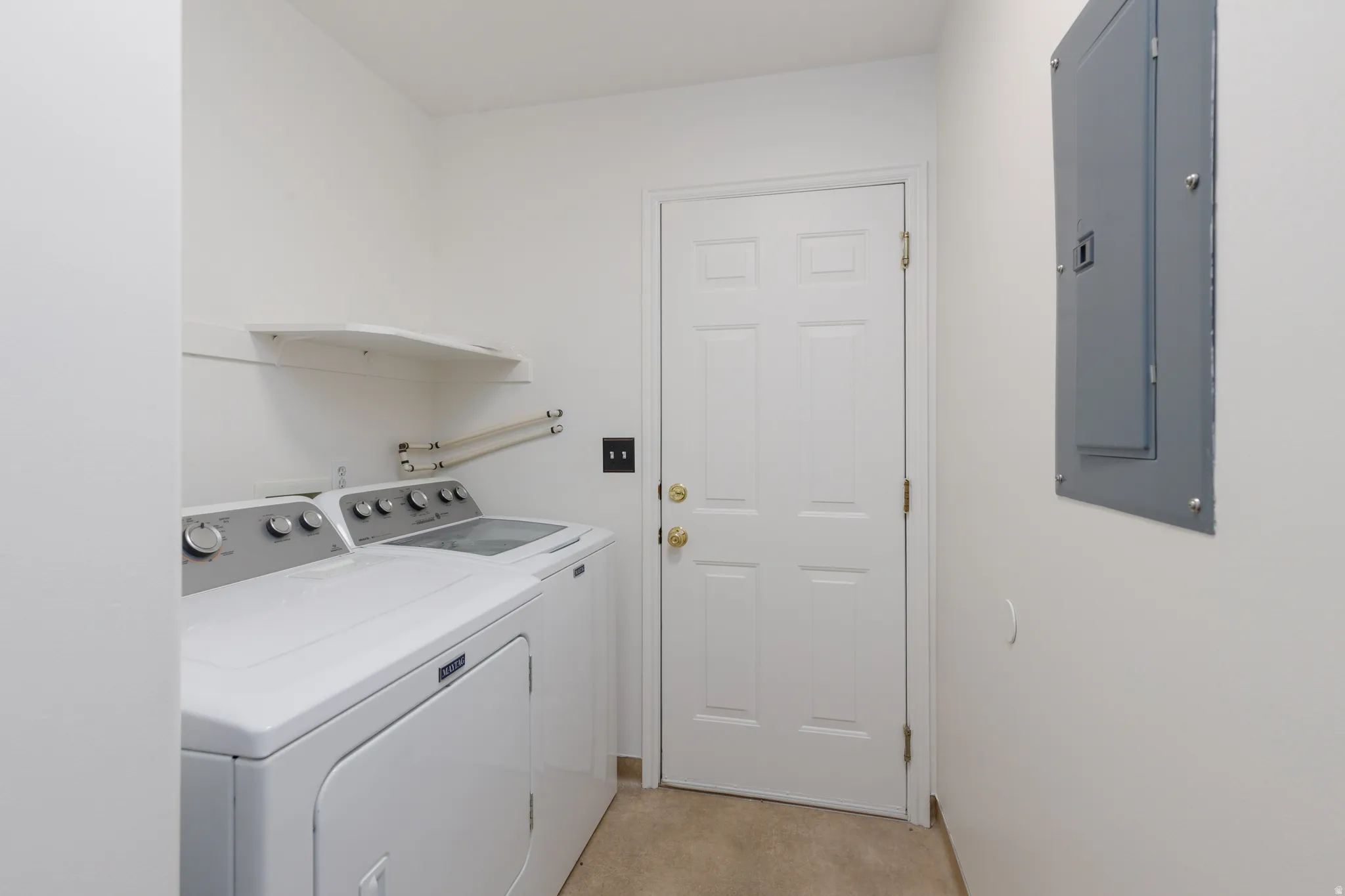 Laundry area featuring white appliances, a wall-mounted shelf, and a panel door