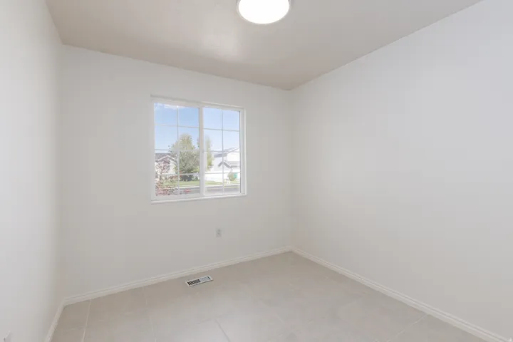 Large window with grid pattern, light-colored tile flooring, and a flush-mount ceiling light