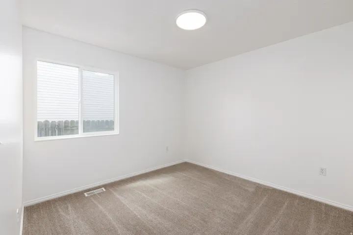 Neutral wall paint, carpet flooring, flush mount ceiling light, white trim, and a window with horizontal blinds