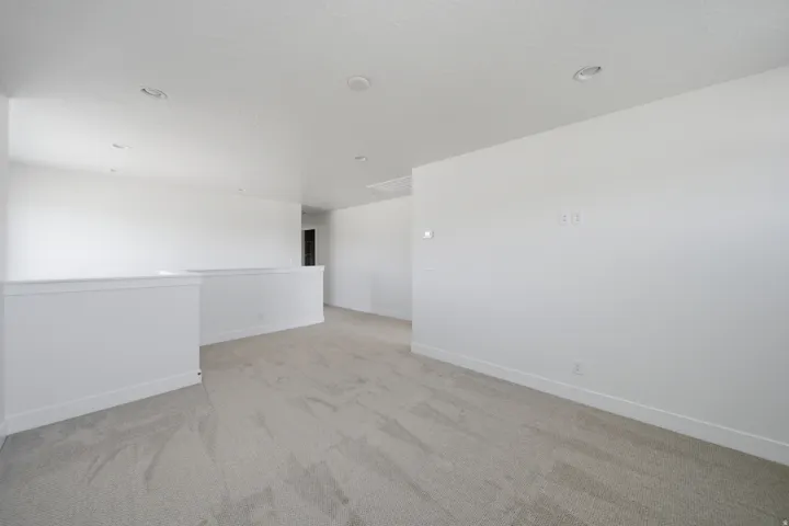 Recessed lighting, plush carpet flooring, and a half-wall partition
