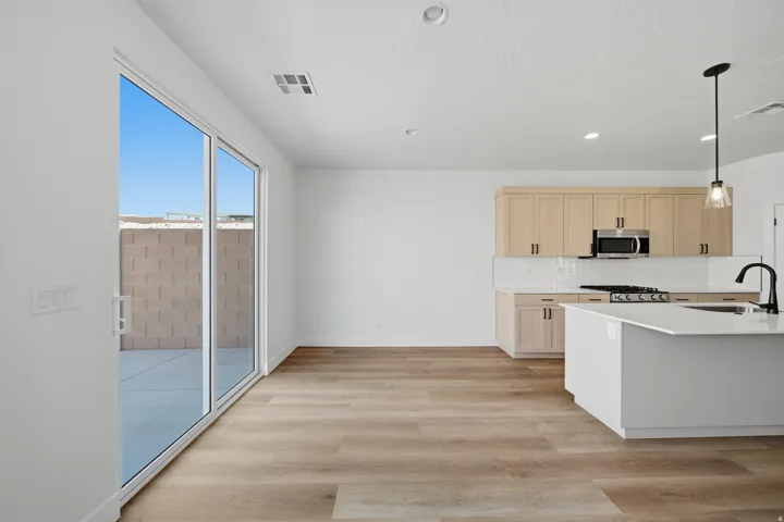 Open-concept kitchen with light wood-finish cabinetry, stainless steel appliances, a white subway tile backsplash, and a large island featuring a black gooseneck faucet