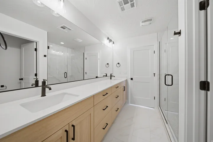 Double vanity with light wood-finish cabinetry, white countertop, and integrated sinks