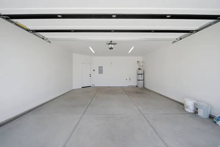 Spacious garage with a concrete floor, bright overhead lighting, and white painted walls