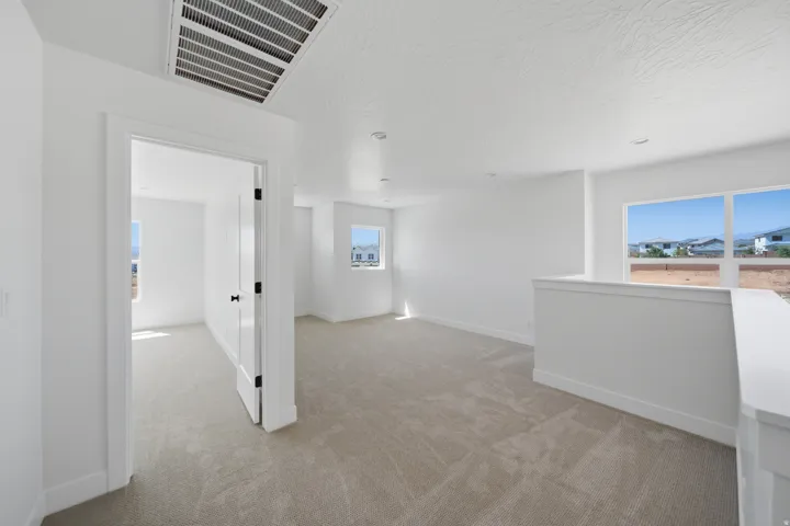 Open-concept room featuring light-colored carpeting, white walls, multiple windows, and recessed lighting