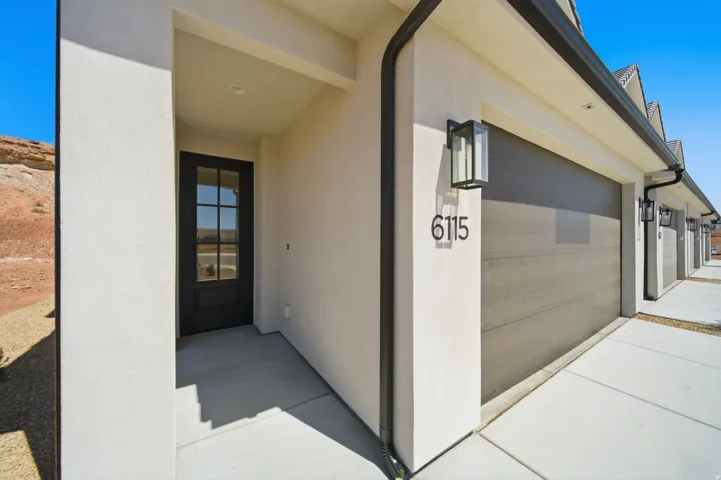 Stucco exterior with a covered entry, dark-paneled garage door, and contemporary exterior lighting