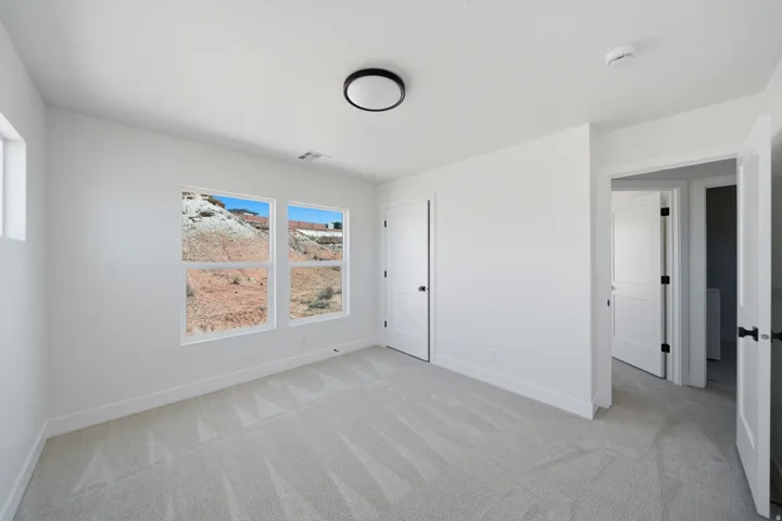 Bright interior with white walls, light-toned carpet, and multiple windows