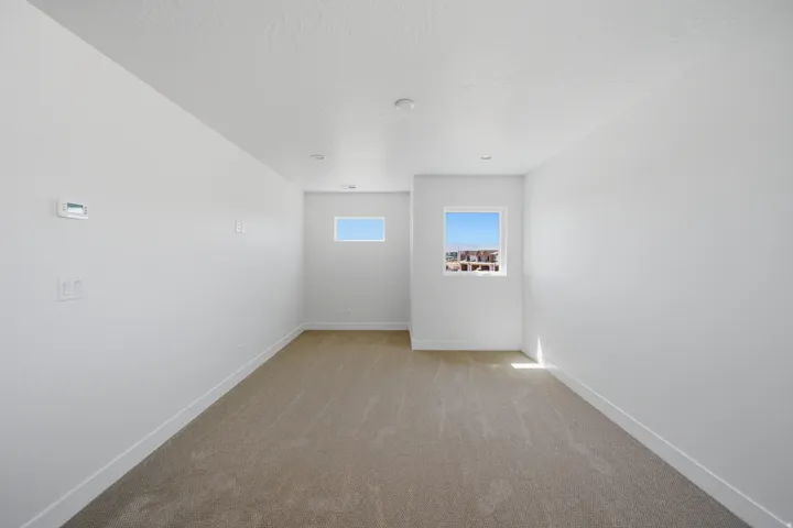 Recessed lighting illuminates the neutral-toned carpeted flooring and white walls