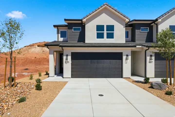 Contemporary exterior with stucco and horizontal siding accents, attached garage with a modern door, concrete driveway, and low-maintenance xeriscape landscaping
