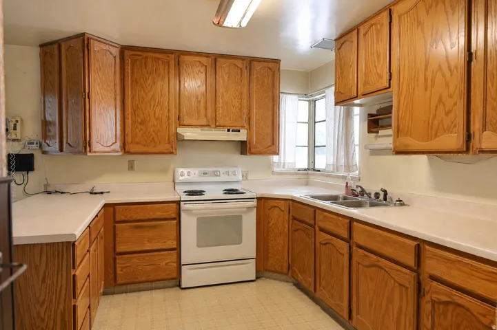 U-shaped kitchen layout featuring wood cabinetry, light-toned countertops, and a double basin sink