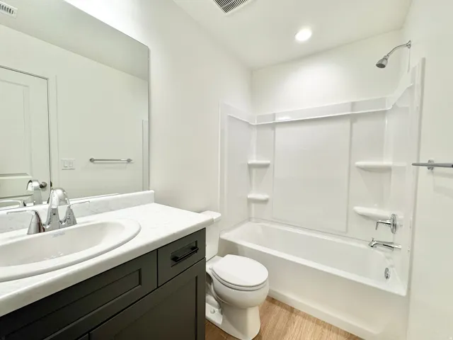 White vanity with a light-toned countertop, complete with an undermount sink and chrome faucet