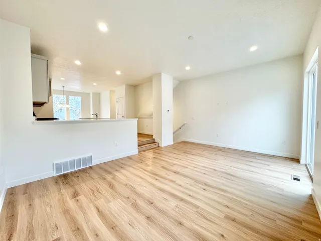 Expansive main living area featuring wood-finish flooring, recessed lighting, and a sliding glass door