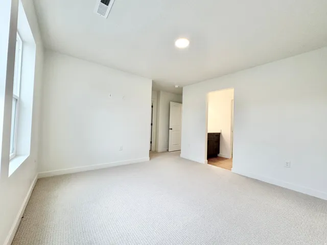 Recessed ceiling lighting, light-toned carpet, white painted walls, white trim, and a window with white casing