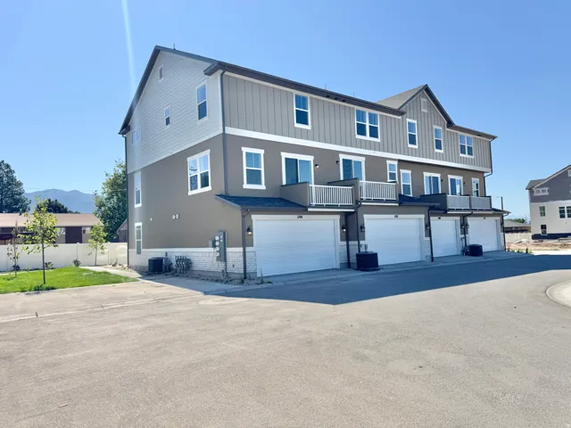 Multi-level townhouse exterior with an integrated garage, individual balconies, and a mountain backdrop