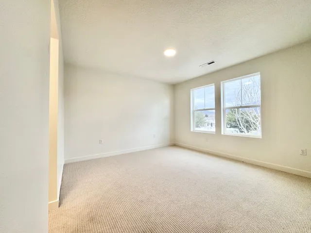 Recessed lighting, neutral wall paint, two windows, and light-colored carpeting
