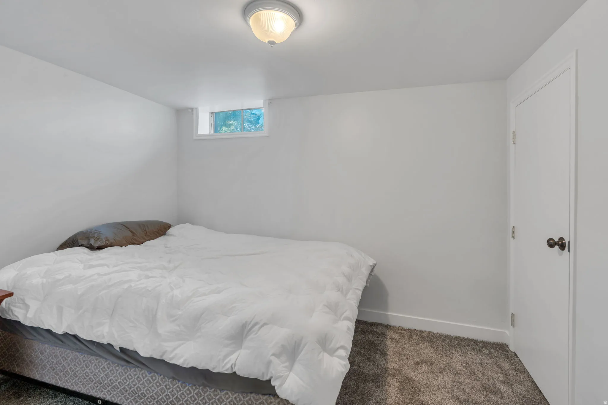 Recessed window, overhead flush mount lighting, white painted walls, carpeted flooring, white door with dark hardware