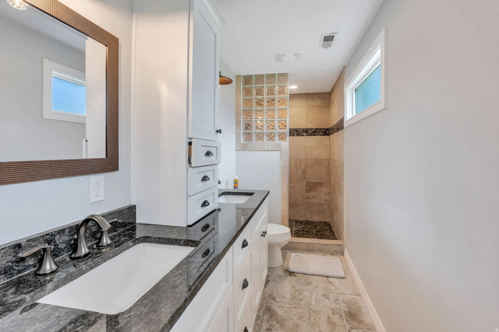 Dual vanity with undermount sinks and dark stone countertops