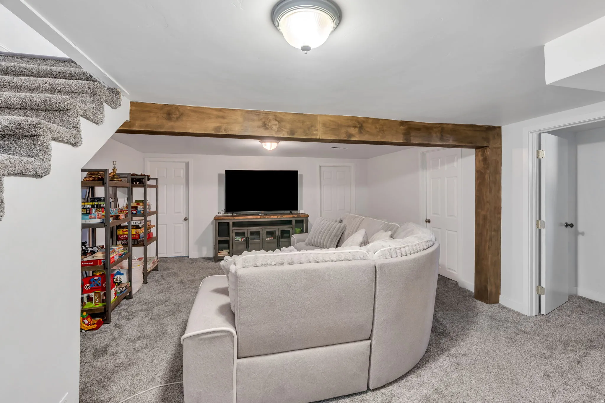 Carpeted flooring, white walls, and a decorative wood beam