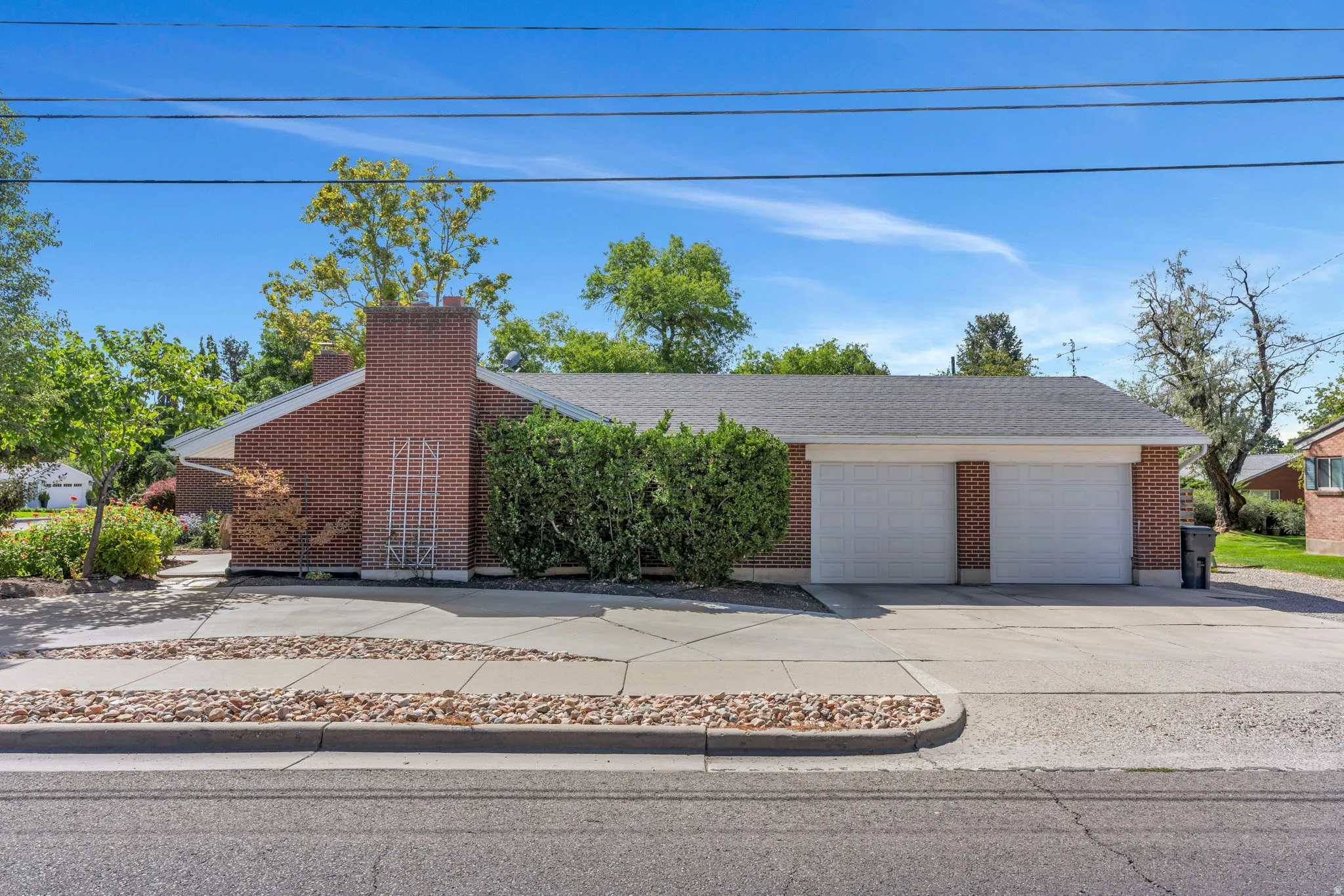 Brick exterior, two-car garage, shingle roof, mature landscaping, and concrete driveway