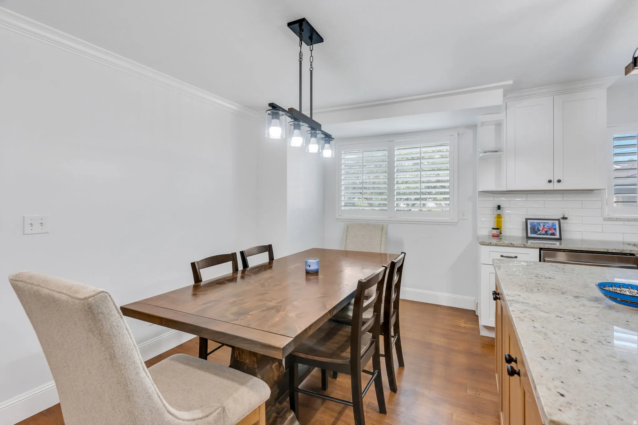Wood-finish flooring, crown molding, and a modern linear chandelier