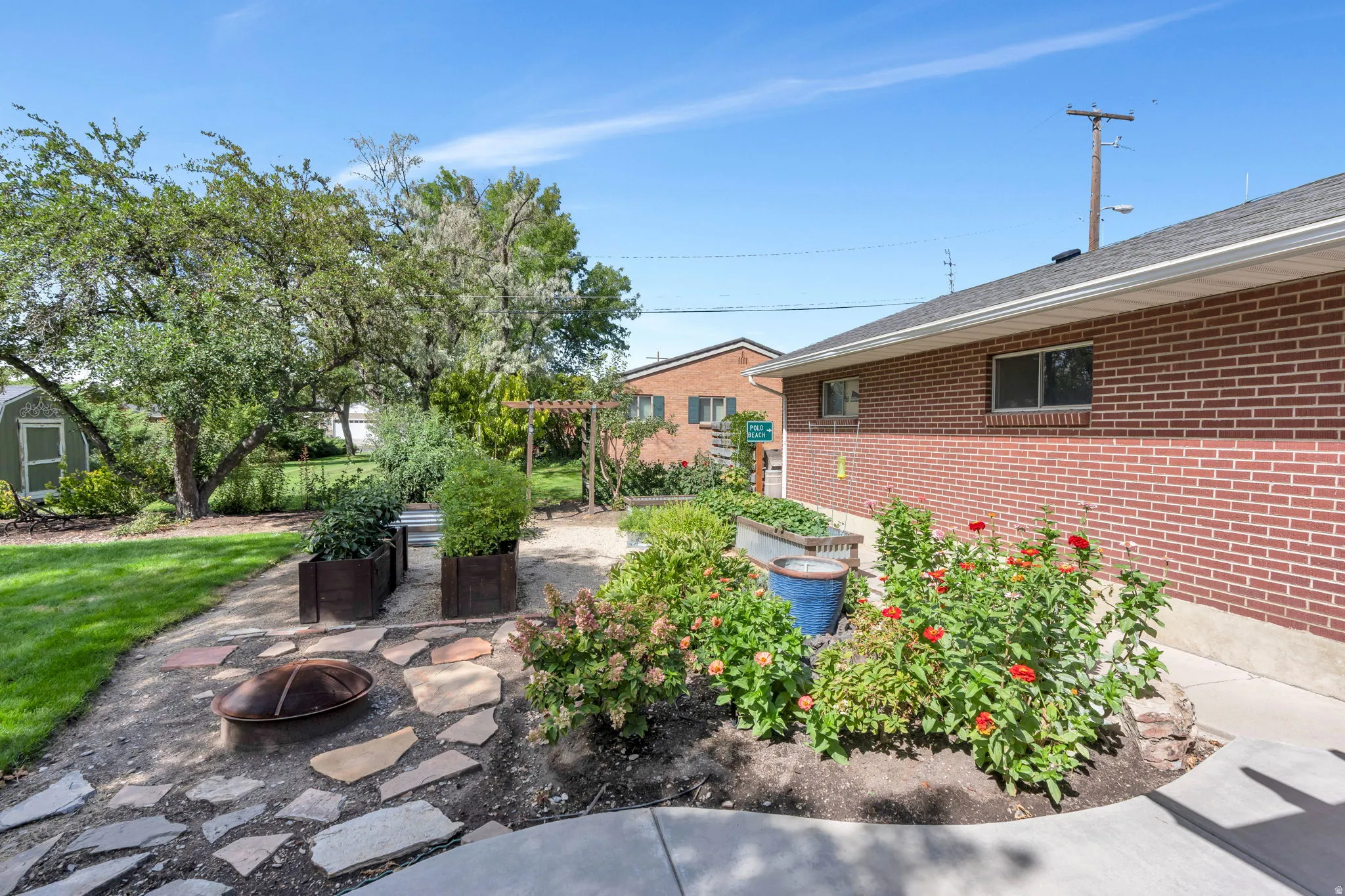 Expansive backyard featuring a manicured lawn, established trees, and stone pathway