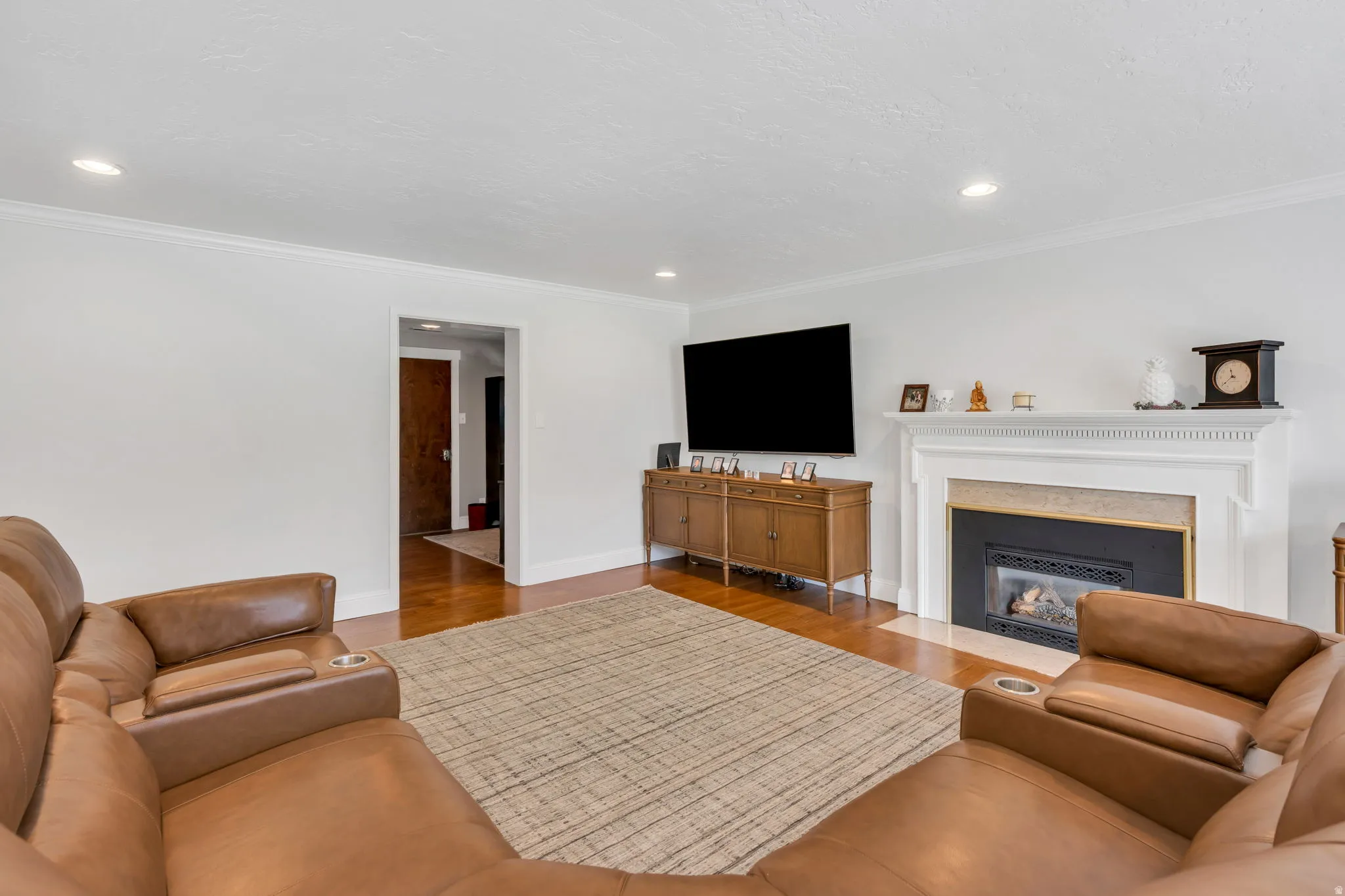 Living area with wood-finish flooring, recessed lighting, and crown molding