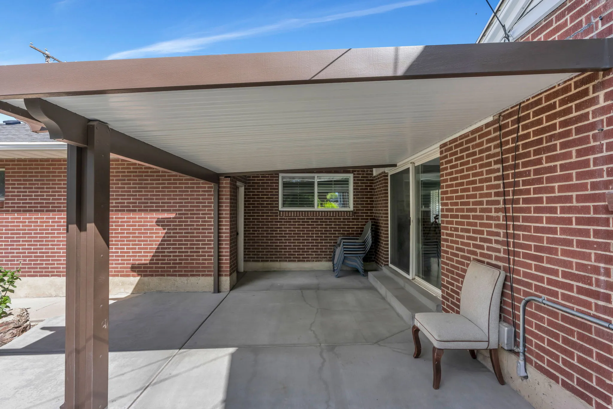 Covered patio with a concrete surface, brick exterior, and sliding glass door access