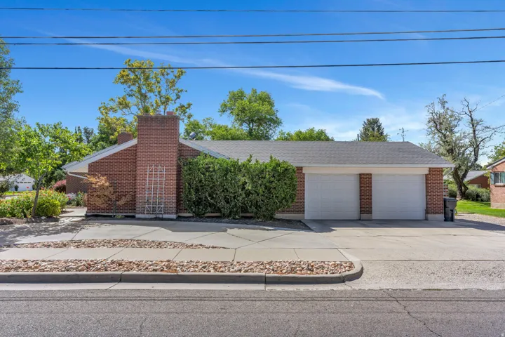 Brick exterior, two-car garage, shingle roof, mature landscaping, and concrete driveway
