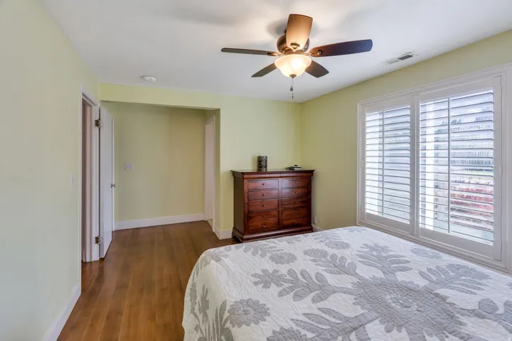 Wood-finish flooring, ceiling fan with integrated lighting, and window with plantation shutters