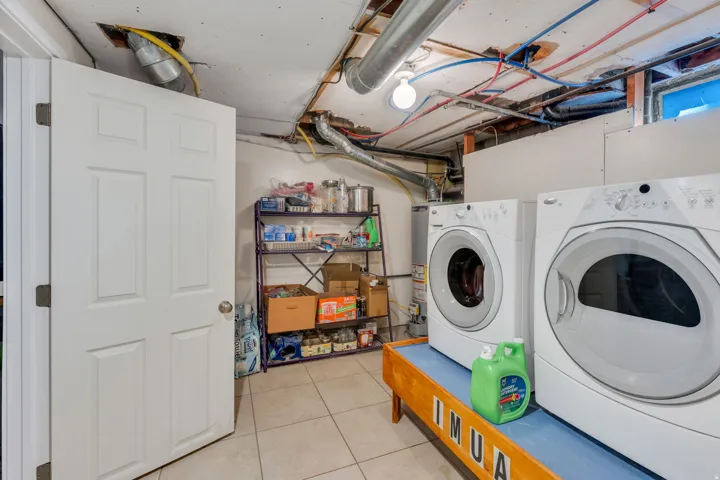 Tiled flooring, white paneled door, exposed ceiling utilities, washer and dryer appliances, metal shelving unit