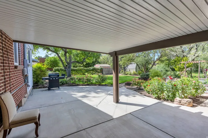 Covered patio featuring a solid roof, structural support beams, and a concrete surface