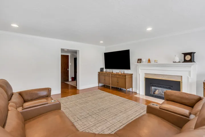 Living area with wood-finish flooring, recessed lighting, and crown molding