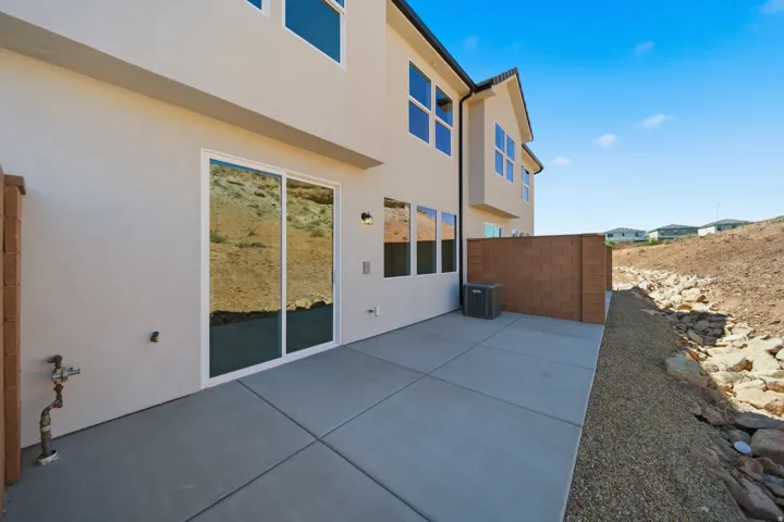 Concrete patio with sliding glass doors, stucco exterior, and a brick privacy wall