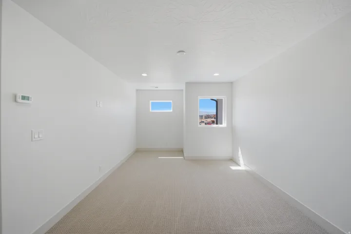 Recessed lighting, wall-mounted thermostat, multiple electrical outlets, neutral carpet, and white walls