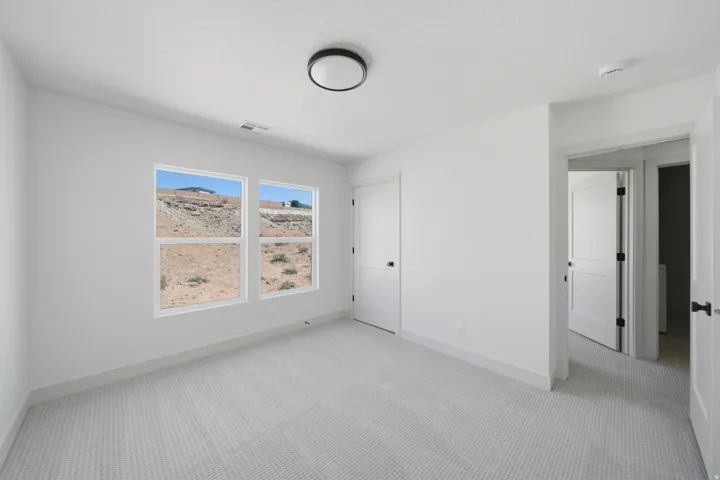 Neutral white walls, textured carpeting, modern flush-mount ceiling light, and interior doors with matte black hardware