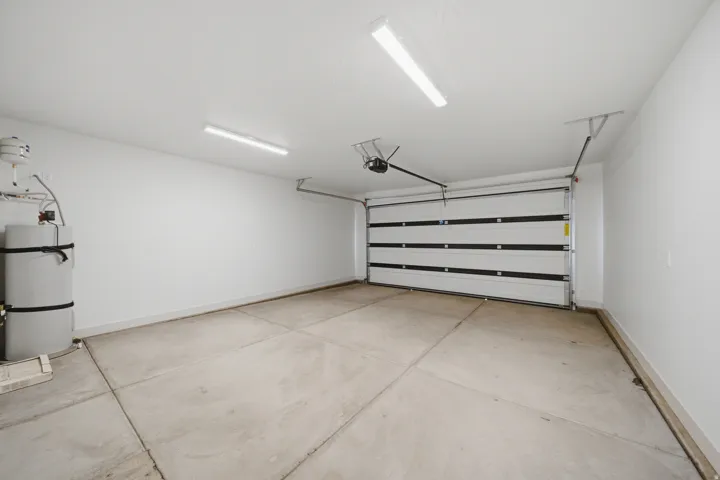 Concrete flooring with white walls, a sectional garage door, and overhead lighting