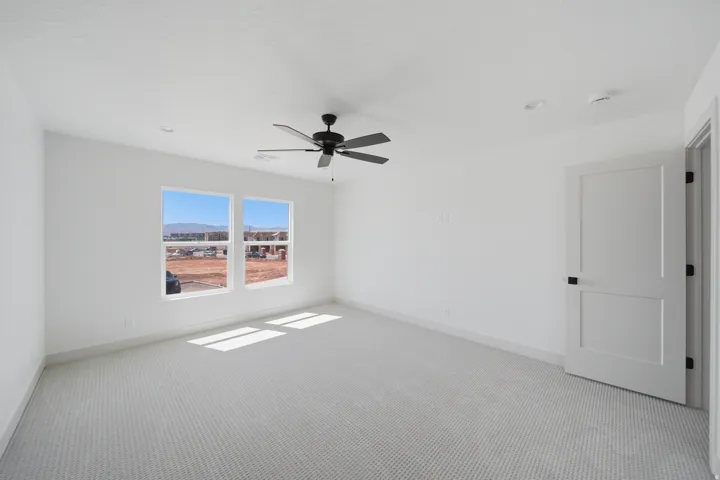 White interior walls, patterned carpet, recessed lighting, white trim, and a ceiling fan with matte black finish