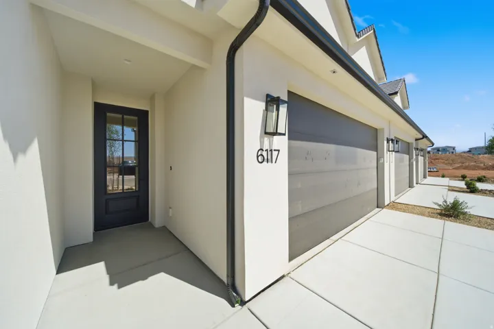 Exterior showcasing a dark-framed glass paneled entry door, a multi-car garage with modern doors, and contemporary exterior lighting fixtures