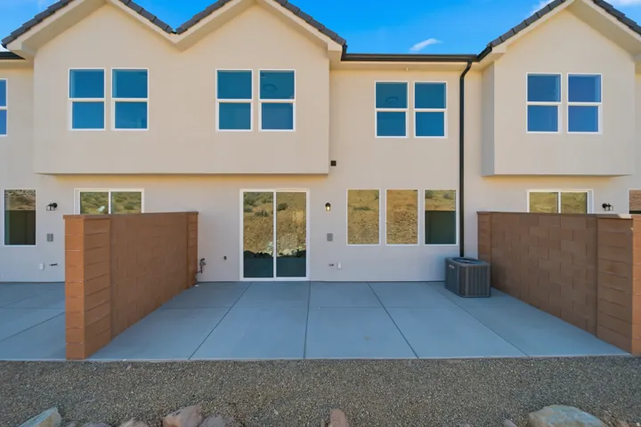 Exterior featuring a stucco finish, multiple pane windows, a concrete patio, and a partial privacy wall