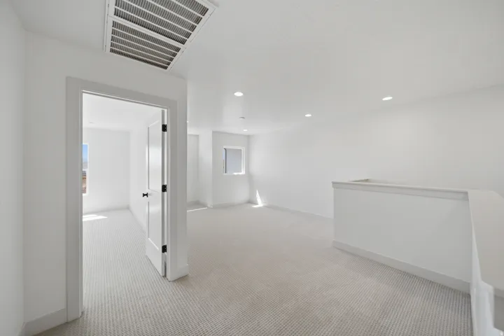 Bright open space featuring recessed lighting, light-toned carpeting, and a white interior door with dark hardware