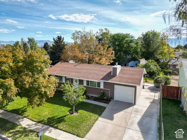 Single-story residence featuring a two-car garage, concrete driveway, and a front yard with mature trees