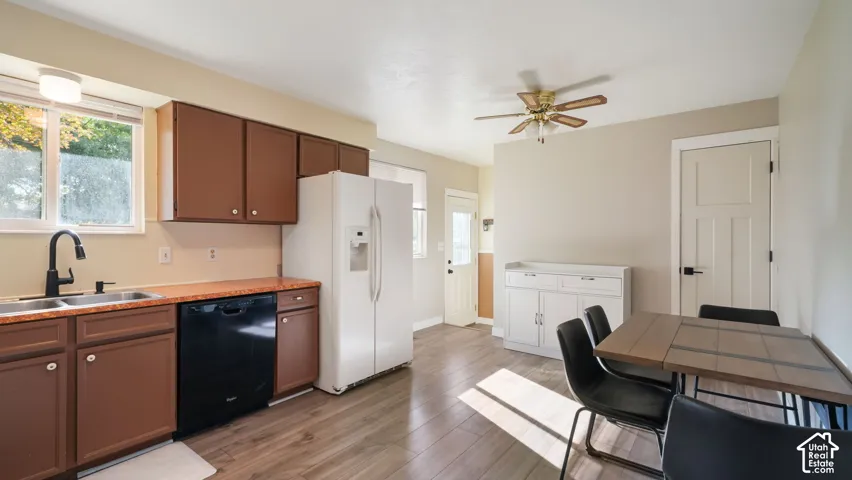 Kitchen with wood-finish flooring, brown cabinetry, stainless steel double-basin sink with matte black faucet, and a ceiling fan