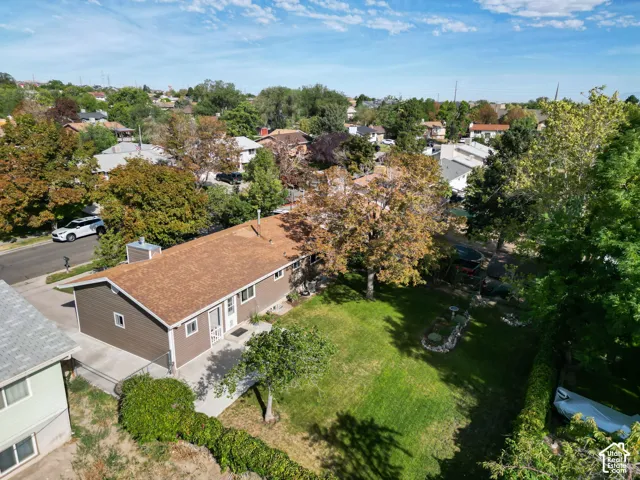 Brown siding exterior with a brown shingle roof, accompanied by a spacious grassy yard and mature trees