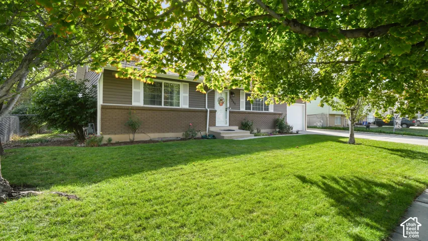 Exterior featuring brown siding, white window shutters, a brick foundation, a white front entry door, and a concrete pathway