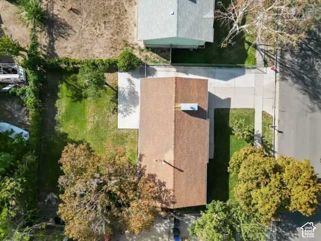 Gable roof with shingle material, concrete driveway, front lawn, mature trees, and established landscaping