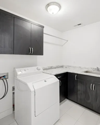 Built-in cabinetry with silver hardware, an integrated stainless steel sink, and light-toned countertops