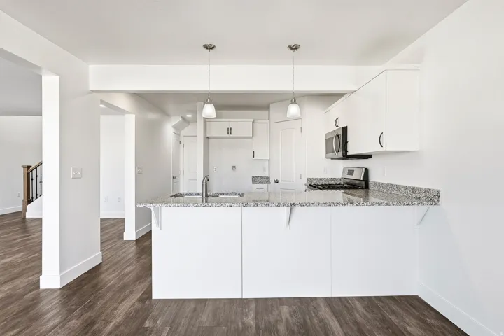 Kitchen featuring white cabinetry, polished granite countertops, stainless steel appliances, and pendant lighting