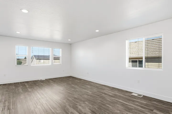 Recessed ceiling lighting, wood-finish flooring, and multiple windows with blinds